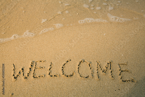 Welcome - handwritten on the soft beach sand.