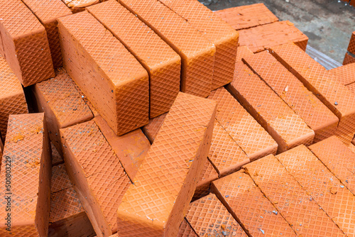 burnt bricks of orange color with corrugated sides lie on a pallet