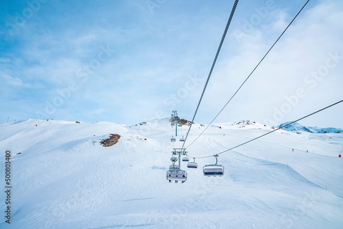Ski lift moving over snow covered landscape. Chairlift on white mountain against blue sky. Idyllic view of alpine region during winter. © Aerial Film Studio