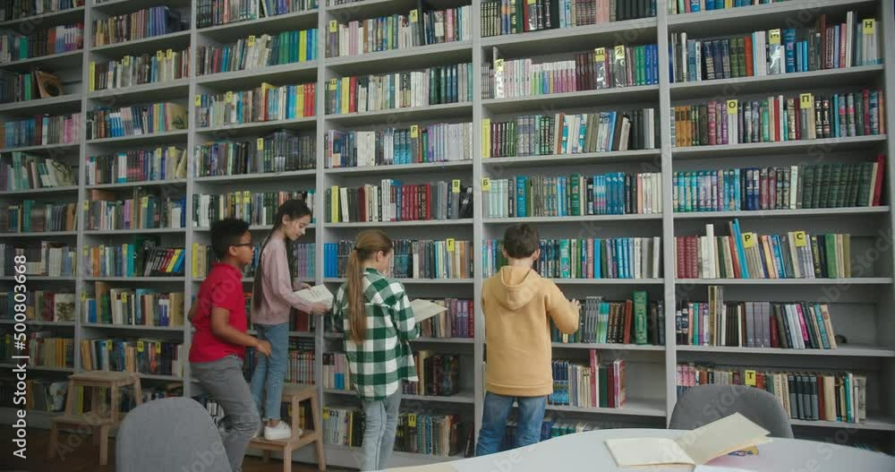 Schoolchildren take books from shelves to read in library Schoolchildren take books from shelves to read in library