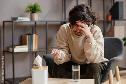 Horizontal medium portrait of young Caucasian man feeling stressed out having psychologist appointment sitting on chair lowering his head