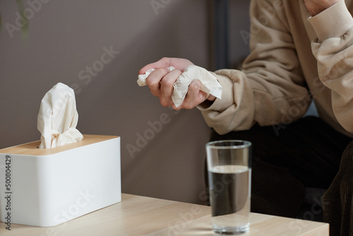 Horizontal close-up of unrecognizable man suffering depression having psychologist appointment siiting at table with glass of water