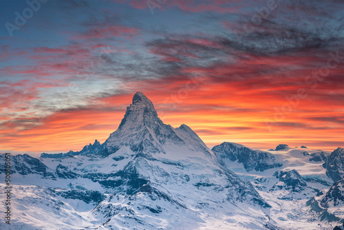 Scenic view of snowcapped matterhorn mountain against cloudy sky. Beautiful famous snow covered landscape during sunset. Magnificent white valley in alps during winter.