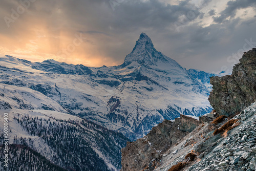 Beautiful snowcapped matterhorn mountain peak during sunset. Scenic view of famous snow covered landscape against cloudy sky. Snowy valley in alps during winter.