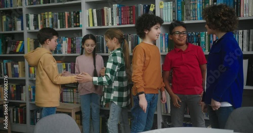 Kids play fun game near boys talking in school library