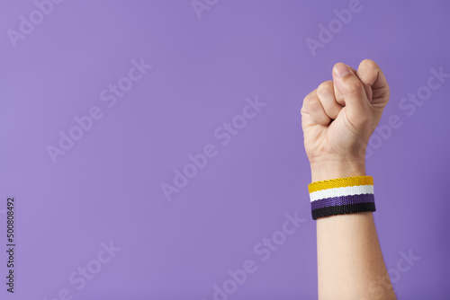 Raised fist of a person wearing a non binary flag bracelet. Gender identity diversity. photo