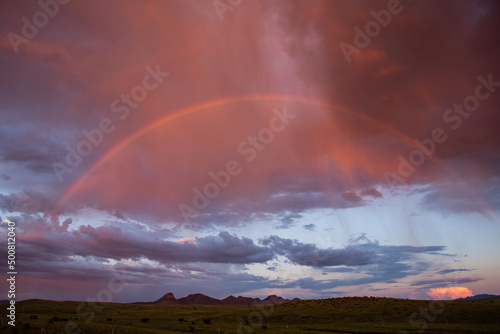 Rainbow at sunset over grasslands and mountains