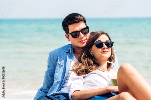 Vacation romantic love young happy smile couple in honeymoon travel holiday trip sit on sand at blue sky sea beach having fun and relaxing together on tropical beach.Summer travel