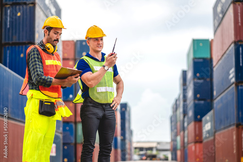 Professional engineer container cargo foreman team in helmets working standing and using walkie talkie checking stock into container for loading.logistic transport and business industry export photo