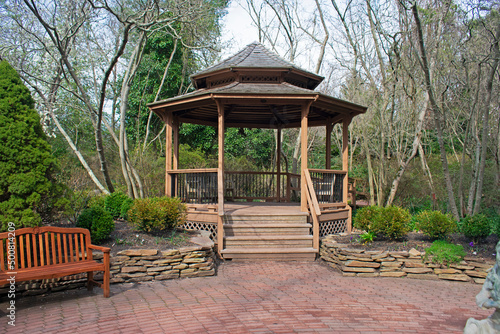 View of wooden gazebo and raised planter on a brick footpath -05