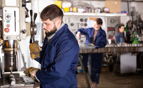 Portrait of confident man mechanic using drilling machine in workshop