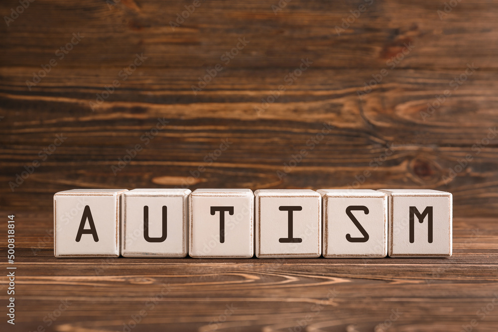 Word AUTISM made of cubes on wooden background