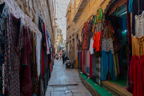 Jaisalmer, Rajasthan, India - October 13, 2019 : Colourful clothes are being sold in market place Inside Jaisalmer Fort or Golden Fort, in the morning light. UNESCO world heritage site at Thar desert. © mitrarudra