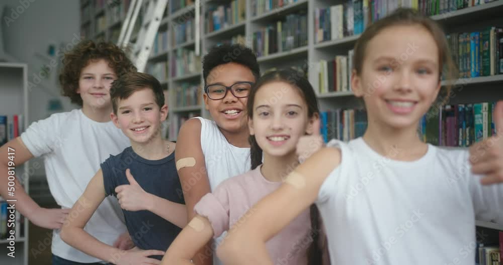 Multinational children stand in library after vaccination