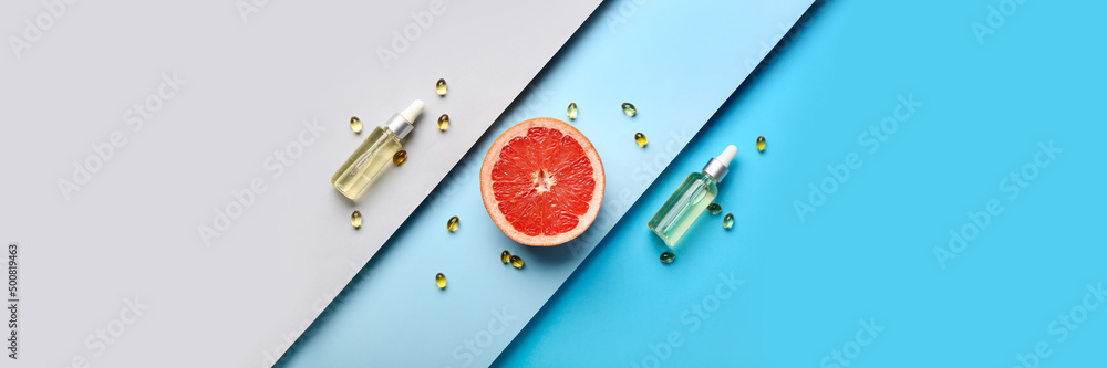 Cosmetic bottles with vitamins and grapefruit slice on color background. Banner for design - obrazy, fototapety, plakaty 