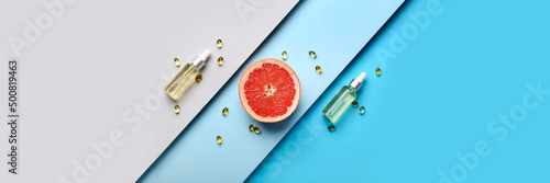 Cosmetic bottles with vitamins and grapefruit slice on color background. Banner for design