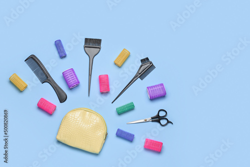 Composition with cosmetic bag, hairdresser's tools and curlers on blue background