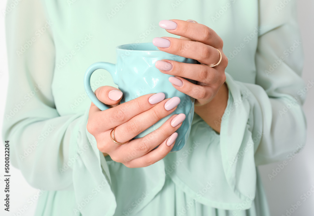 Young woman with beautiful manicure holding cup on light background, closeup Young woman with beautiful manicure holding cup on light background, closeup