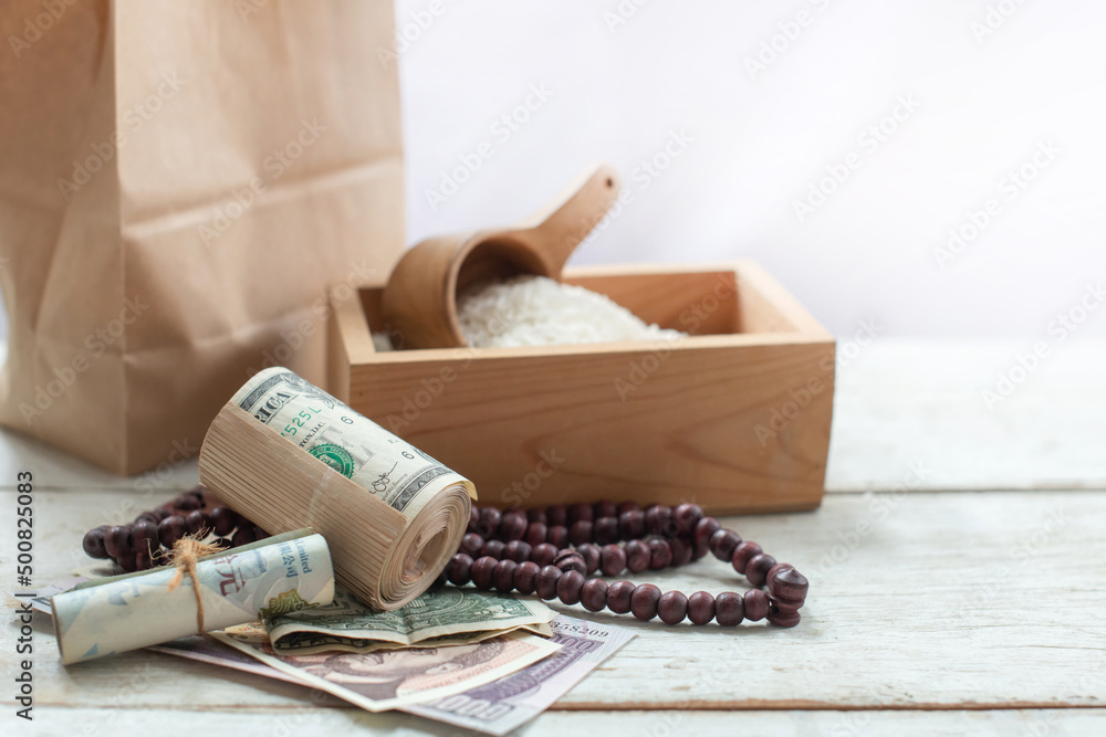 Banknote, rosary, brown paper bag and rice in the wooden box, ZAKAT donation for Muslims according to religious principles during the Ramadan month