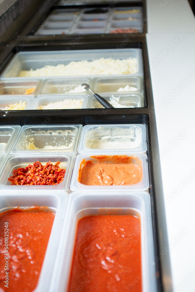 A view of a station full of pizza toppings and ingredients, seen at a local pizzeria. A view of a station full of pizza toppings and ingredients, seen at a local pizzeria.