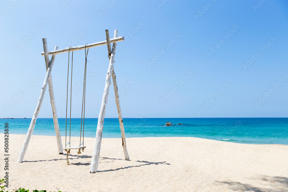 Wooden swing on beautiful beach background, relax by the sea, summer holiday destination, vertical style Wooden swing on beautiful beach background, relax by the sea, summer holiday destination, vertical style