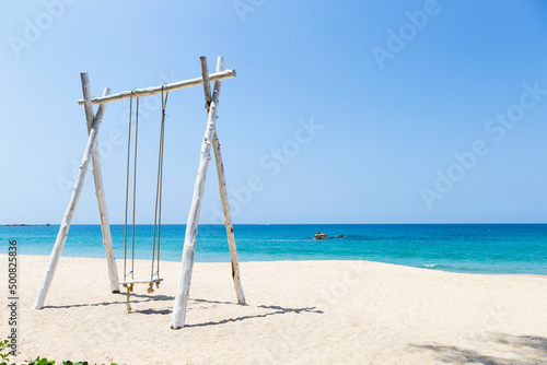 Wooden swing on beautiful beach background, relax by the sea, summer holiday destination, vertical style