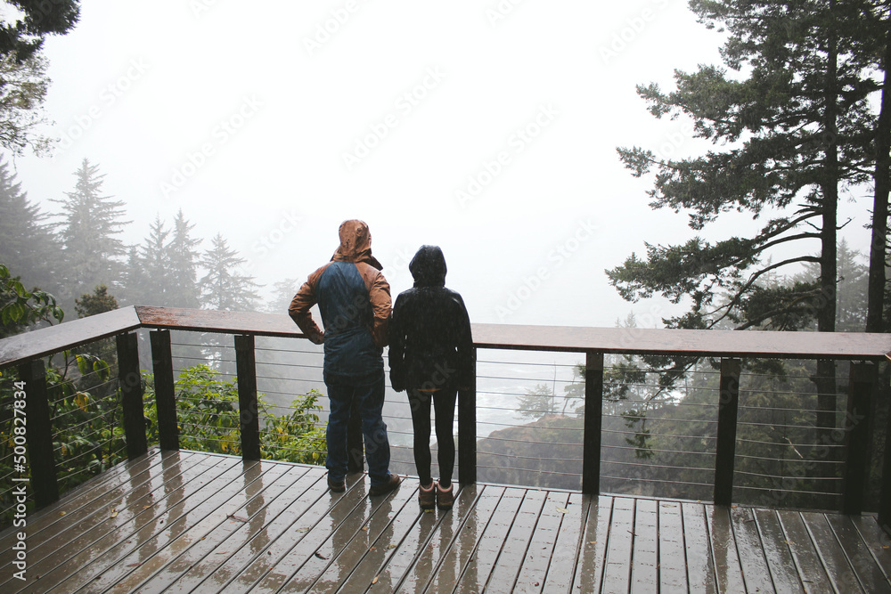 A view of a couple viewing the Natural Bridges Viewpoint during a misty storm.
