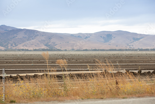A view looking a large field of soil and irrigation pipe systems, ready for the next round of crops, seen in the farmlands of Gilroy, California.