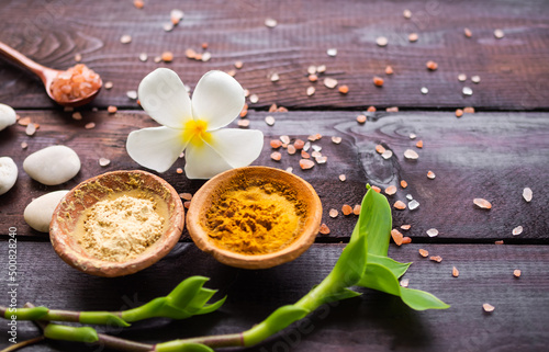 Organic pure Powder Turmeric and Tanaka clay cup with fresh frangipani flowers perfumery,himalaya salt on wooden background. ancient herb herbal of thailand. Aromatherapy Spa set.massage oriental. photo