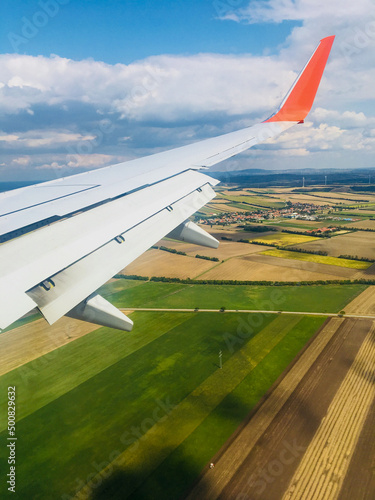 Beautiful view from the window on the wing of the aircraft and the multi-colored landscape of Austria. The plane is preparing to land in Vienna. Vertical. Vienna, Austria