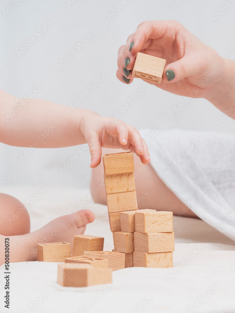 Φωτογραφία Mom is playing with a child, building a house out of wooden eco-friendly cubes, close-up