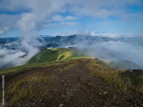 Clouds moving over green mountain range