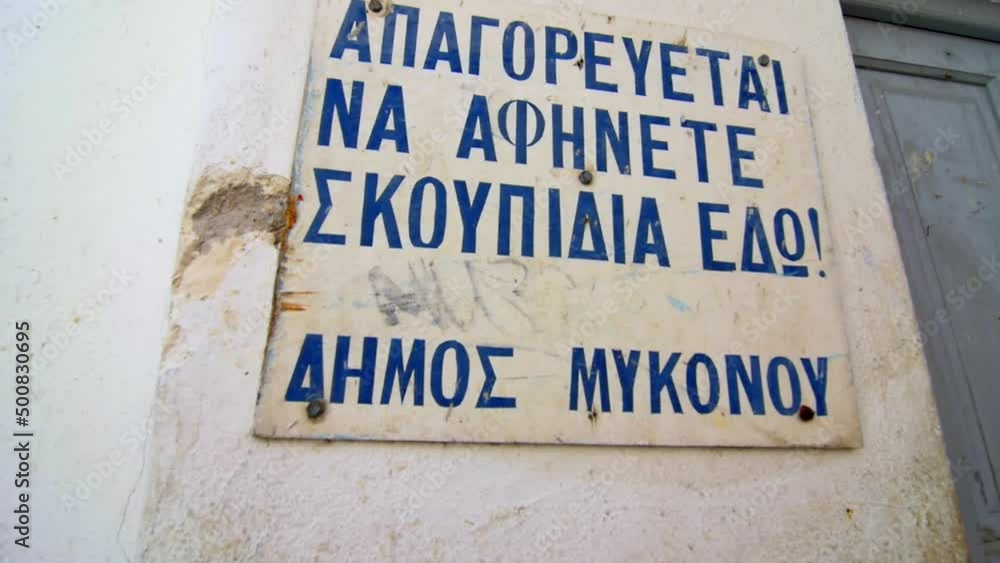 sign in detail with inscriptions in greek what say something on the white background of touristic Mykonos town during a nice day sign in detail with inscriptions in greek what say something on the white background of touristic Mykonos town during a nice day
