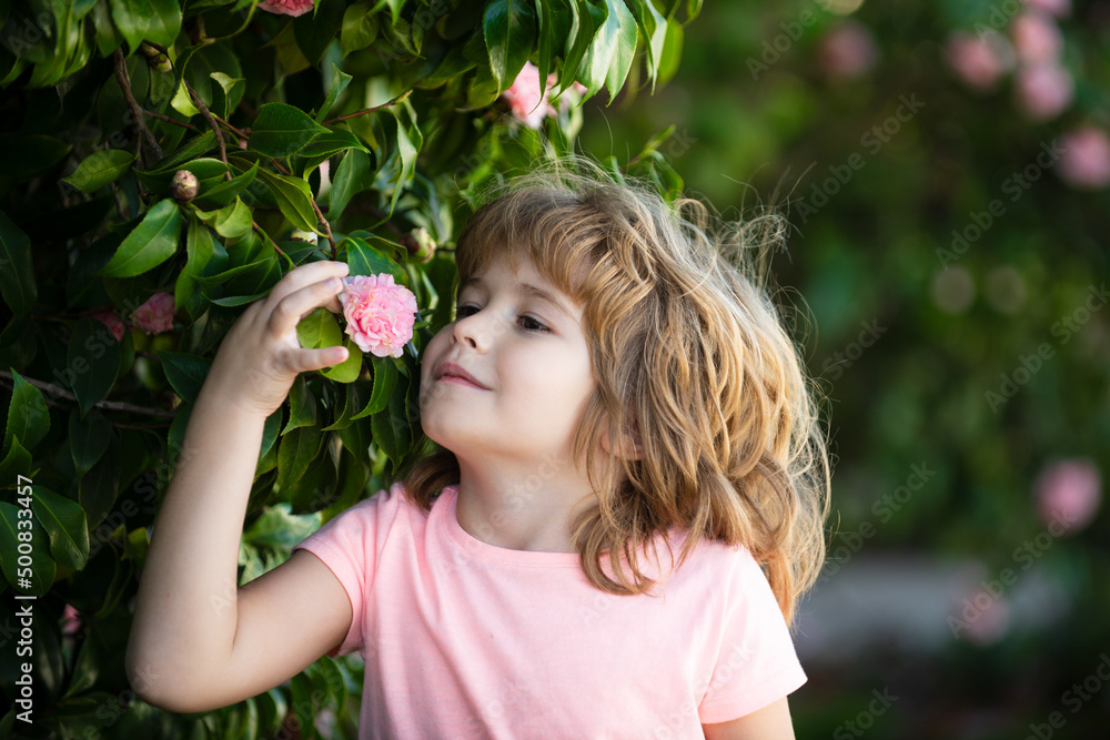 Spring child face. Close up portrait of a small blond child with spring flower. Funny kids in backyard. Kids close up face on blossom background. Children girl play in spring flowers. Spring child face. Close up portrait of a small blond child with spring flower. Funny kids in backyard. Kids close up face on blossom background. Children girl play in spring flowers.
