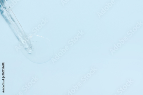 Liquid transparent hyaluronic or retinol serum or gel with vitamin c on a blue background. Open the lid of the serum dropper. Light background with daylight and gel texture look. Skin care products