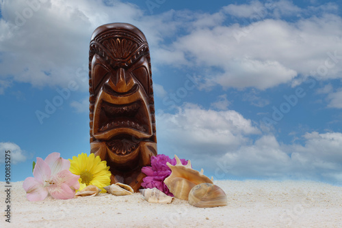 Antique Wooden Mask From Hawaii on Beach With Flowers and Blue Sky