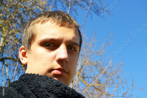 A young autistic guy in a park against a blue sky