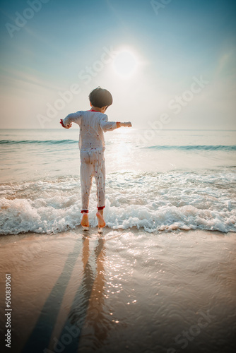 The boy jumped and played in the morning sea waves, still wearing his pajamas.