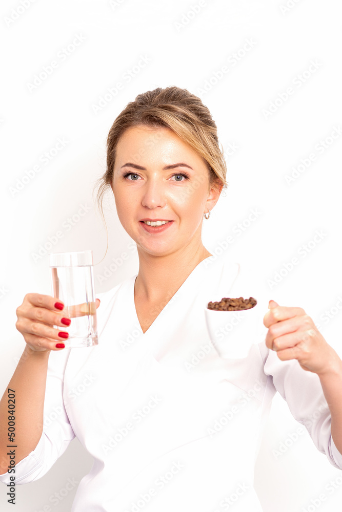 Coffee with water. The female nutritionist holds a cup of coffee beans and a glass of water in her hands on white background Coffee with water. The female nutritionist holds a cup of coffee beans and a glass of water in her hands on white background