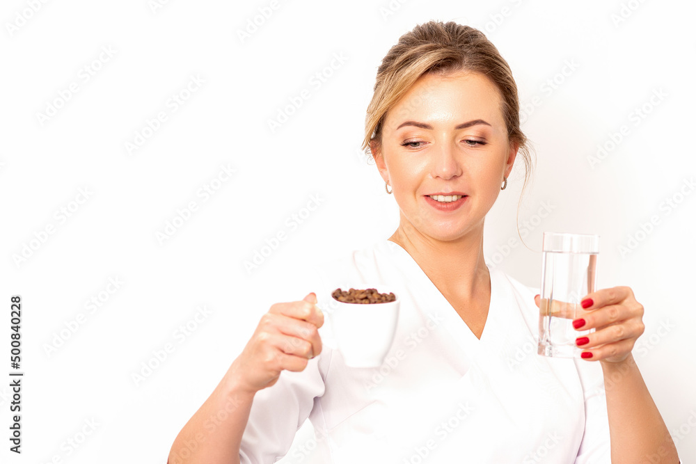Coffee with water. The female nutritionist holds a cup of coffee beans and a glass of water in her hands on white background Coffee with water. The female nutritionist holds a cup of coffee beans and a glass of water in her hands on white background