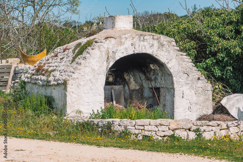 Beautiful white traditional old stone outdoor oven or fireplace in the countryside in Puglia region, Italy