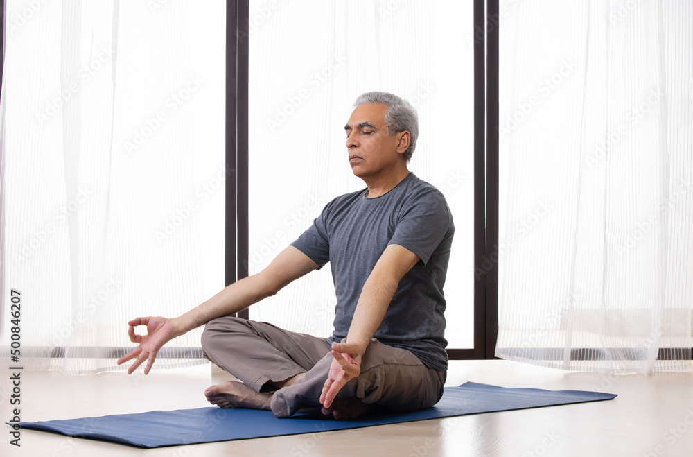 Fototapeta premium Portrait of an active senior man meditating at home