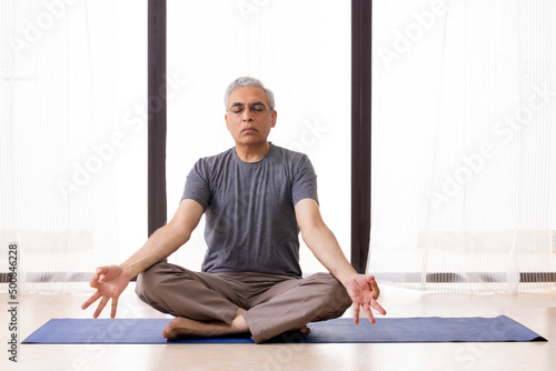 Portrait of an active senior man meditating at home