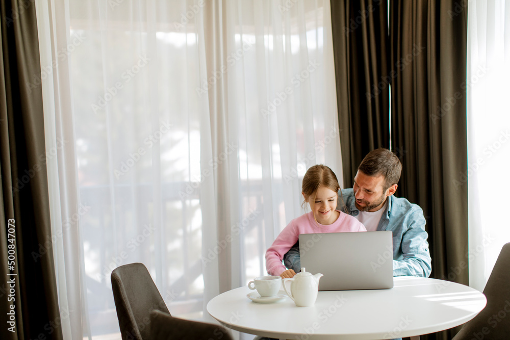 Father and daughter using laptop computer together