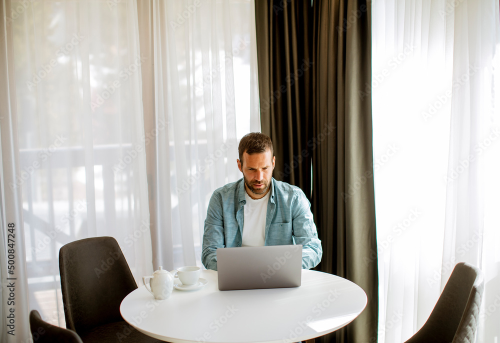 Young man using laptop and drink tea in the living room Young man using laptop and drink tea in the living room