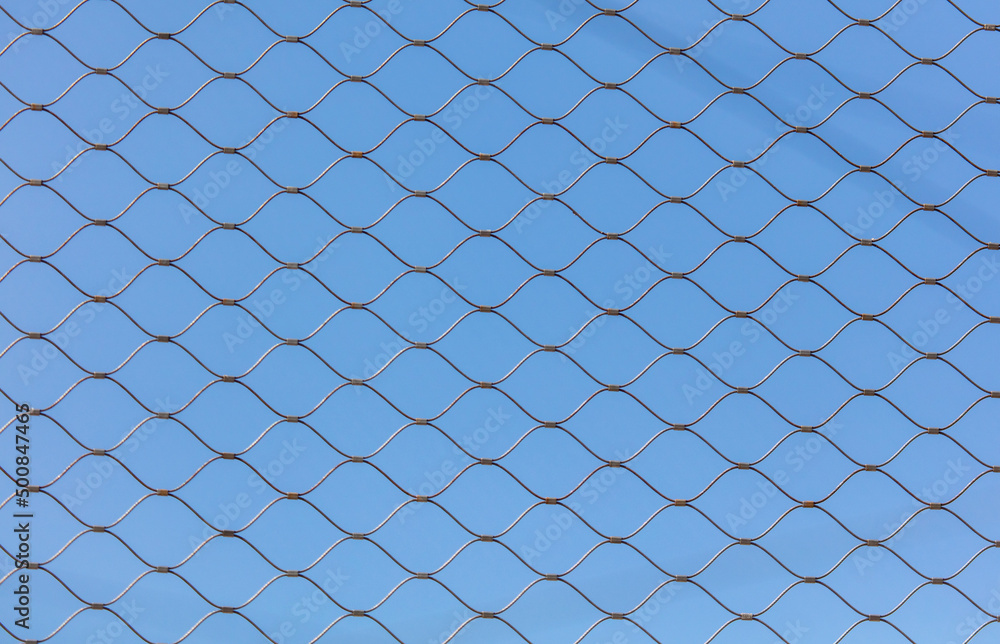 Fototapeta premium Metal mesh against the blue sky.