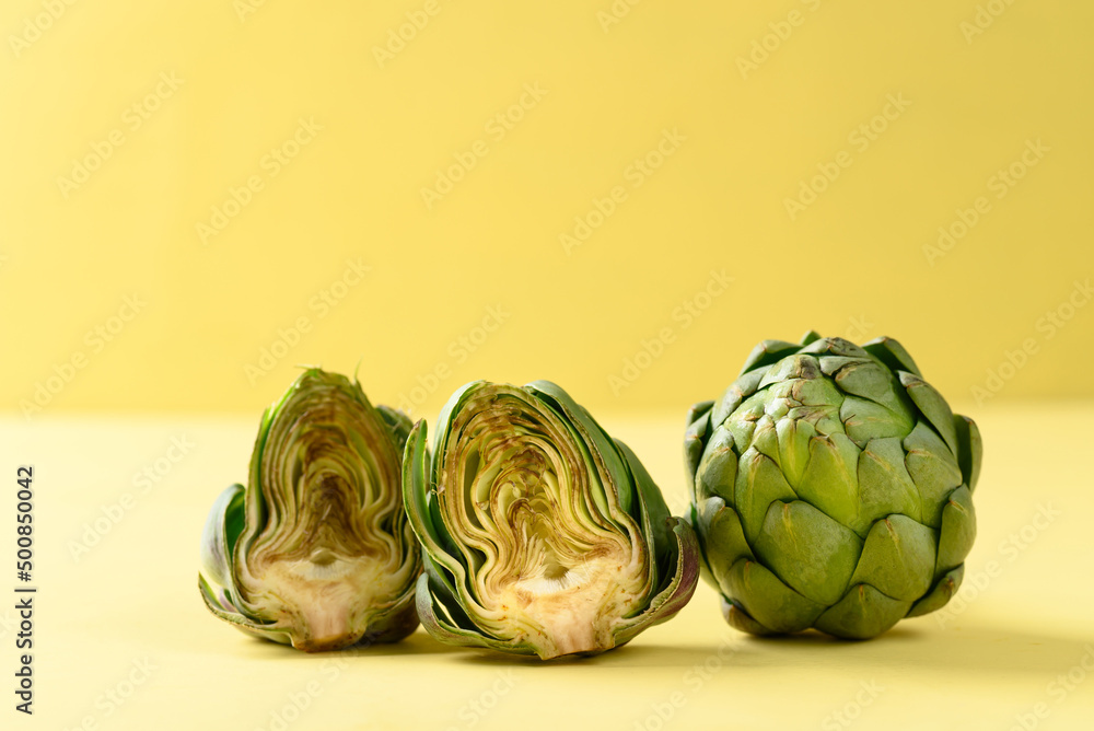Obraz premium Half green artichoke on yellow background, Edible flower bud