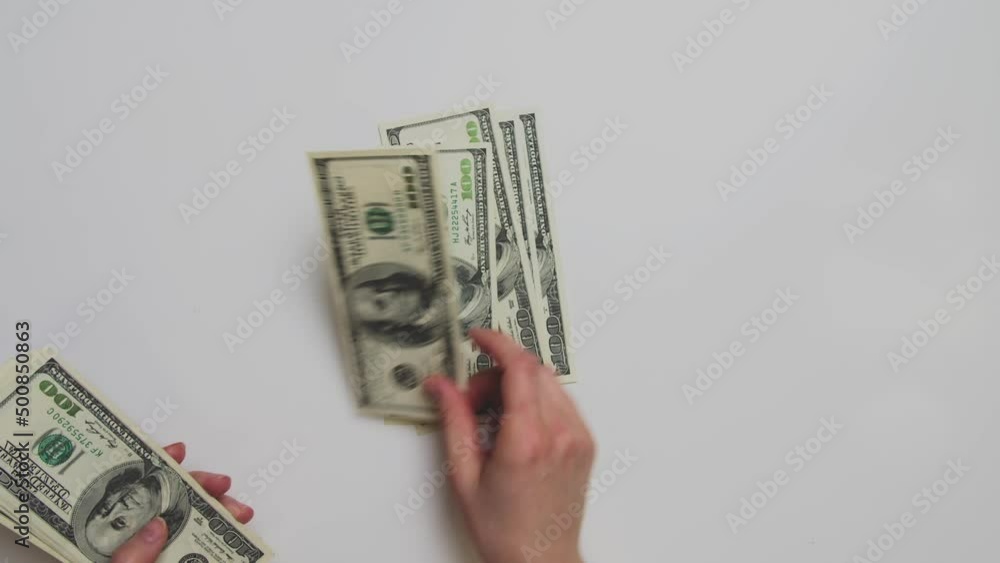 Hands with deft and quick movements count a pack of one hundred dollar bills. The person puts them one by one in a pack on the table Hands with deft and quick movements count a pack of one hundred dollar bills. The person puts them one by one in a pack on the table