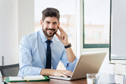Businessman using laptop while sitting at office desk and working
