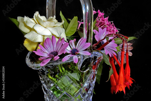 Close up image of a Glass Vase full of mixed colourful fresh flowers. Isolated on black. photo